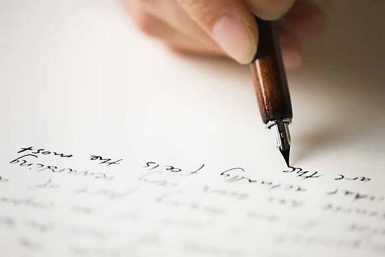 A picture of someone with a fountain pen writing a letter.